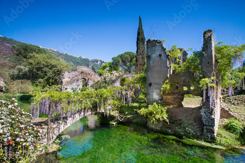 View of the river Ninfa among trees and ruins in spring in Garden of Ninfa, Lazio, Italy