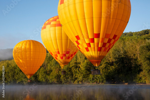 hot air balloons fly low over dordogne river in southern france