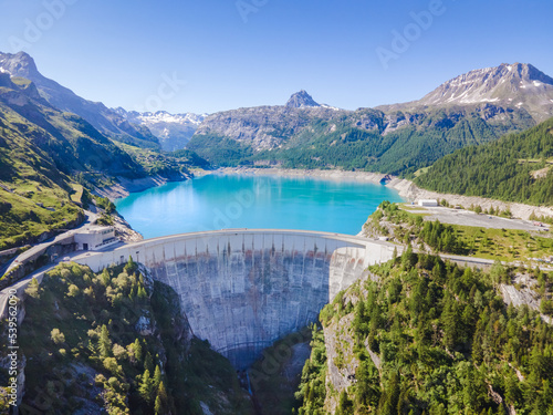 Water dam and reservoir lake aerial view in Alps mountains in summer generating hydroelectricity. Low CO2 footprint, decarbonize, renewable energy, sustainable development, hydro power.