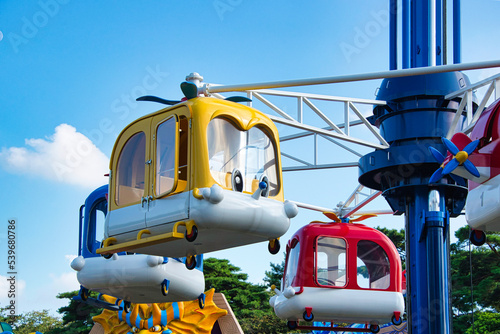青空を背景に、楽しい遊園地のカラフルな空飛ぶ乗り物
