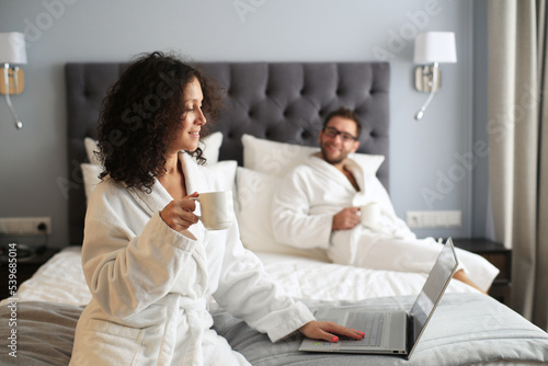 Couple in white bathrobe on a bed in a hotel. Morning in the hotel room.