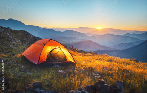 tourist tent camping in mountains at sunset