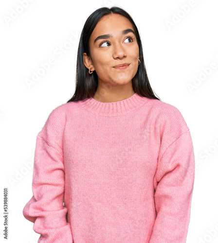 Young asian woman wearing casual winter sweater smiling looking to the side and staring away thinking.