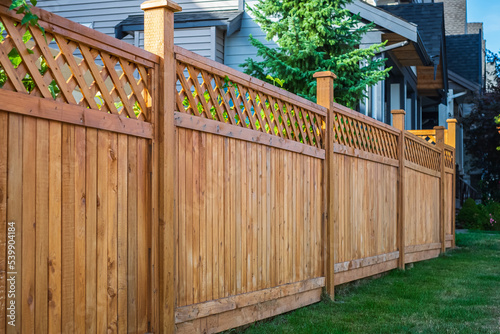 Nice new wooden fence around house. Wooden fence with green lawn. Street photo