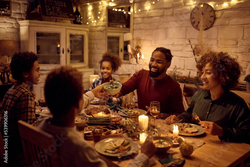 Happy black man having Thanksgiving dinner with his extended family at dining table.