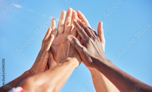 High five, sports and team with support, motivation and solidarity during a game with a blue sky. Group of people, athlete friends or men with hands together for a win, success and partnership