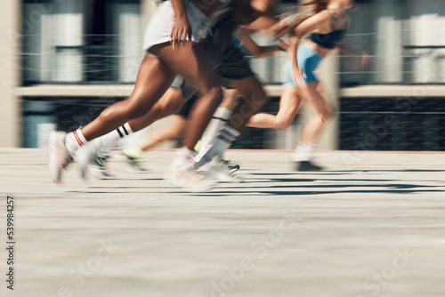 Running, motion and group of people on path together for marathon race, fitness and speed. Fast run team, urban runner club and racing in city street training workout with feet and legs on ground.