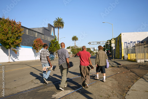 Four young skateboarders walking outdoors 