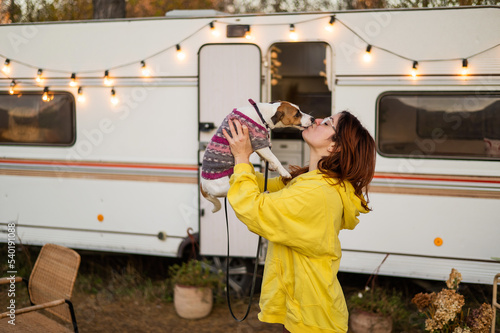 Red-haired Caucasian woman hugs a dog and lives in a motor home. Travel by trailer.