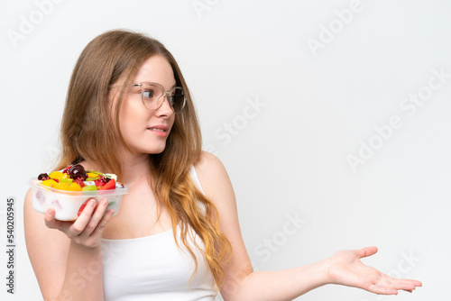 Young pretty woman holding a bowl of fruit isolated on white background with surprise facial expression