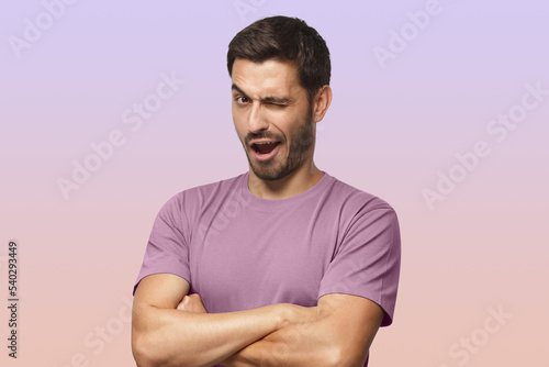 Studio shot of young man winking while flirting on purple background