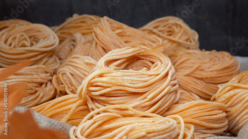 Raw linguini pasta sold in open bags at a street fair. Close-up