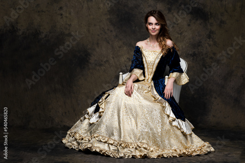 Happy beautiful woman in renaissance royal dress on abstract dark background