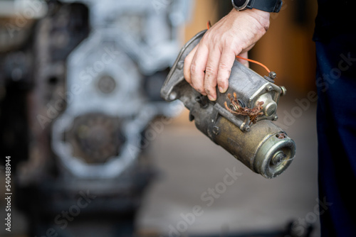 Mechanic man holding starter motor of diesel commonrail engine in heavy machinery workshop