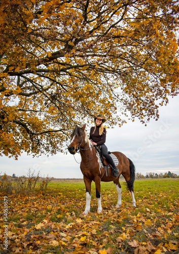 cowboy girl in hat riding horse in autumn field