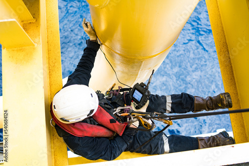 Pipe inspectors in the petrochemical industry by rappelling for inspection and using ultrasonic instruments.
