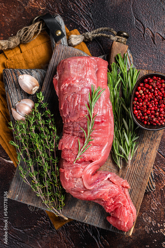 Uncooked beef veal tenderloin, raw meat for fillet mignon steaks. Dark background. Top view