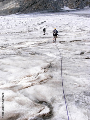 Hikers traveling on the white glacier in the Alps