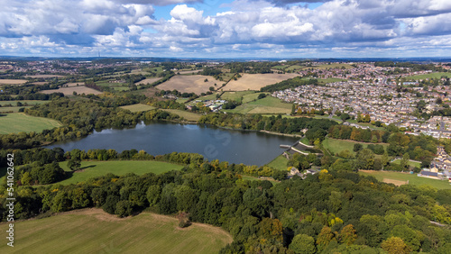 Aerial drone photo of the large Worsbrough reservoir in the village of Worsbrough, Barnsley in Sheffield in the UK, showing the British village and housing estates in the summer time