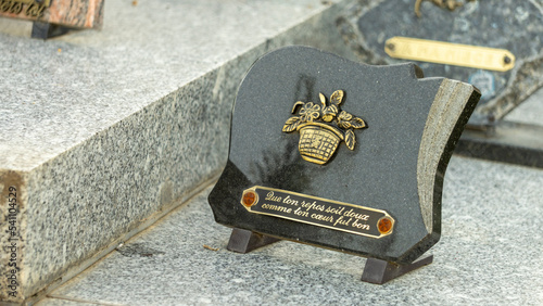 Funerary plaque in black marble, decorated with a flowered basket, with the inscription: "May your rest be sweet as your heart was good"