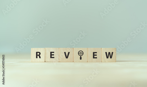 Review text on wooden cube blocks. Review evaluation time for review inspection assessment auditing. Business review for learning, improvement, planning and development for the future.