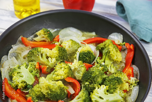 Closeup of pan with steamed vegan vegetables, red paprika, green fresh broccoli, white sweet onions