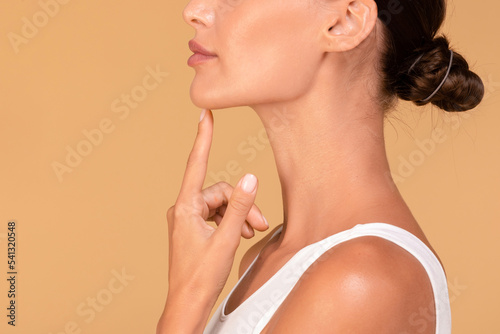 Chin augmentation. Side view of unrecognizable young woman touching her face, happy with result of plastic surgery
