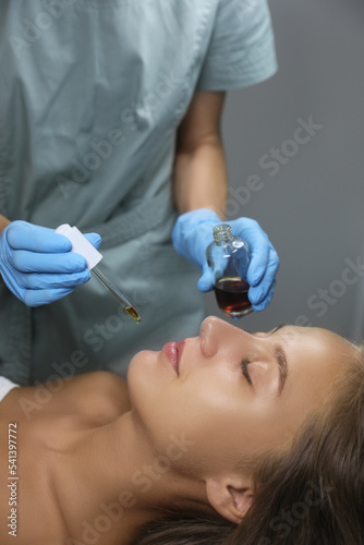 Cosmetologist applying serum on client's face in salon