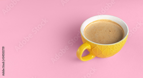 Yellow cup of coffee on a pink background front view. Banner with coffee and copy space for text.