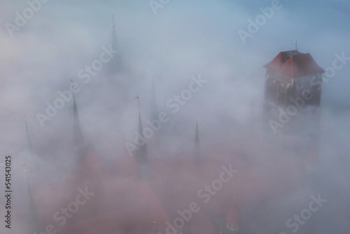 Thick fog over the old town of Gdansk with the St. Marys Basilica tower at sunrise, Poland