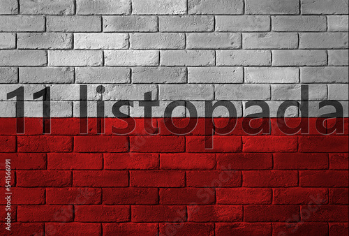 Flaga Polski namalowana na ceglanym murze z napisem święta narodowego 11 listopada