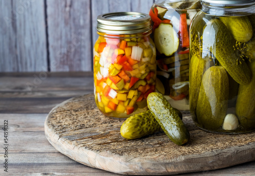 Jars of pickles and peppers against a wooden background.