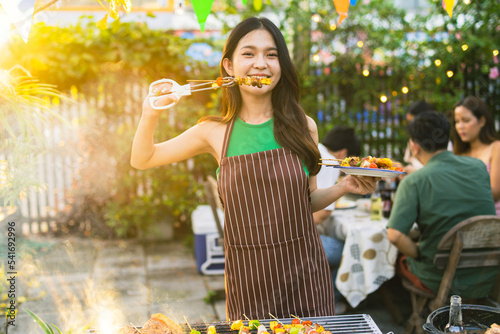 Cute Asian woman grilling for a group of friends.