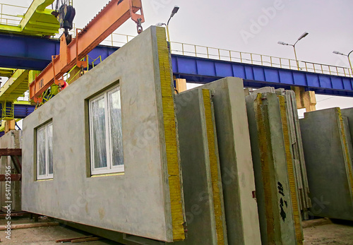 A builder installs a concrete floor slab panel at a construction site.