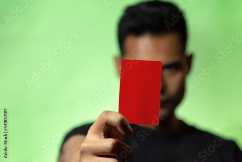  Hombre mostrando tarjeta roja o amarilla en fondo verde concepto de árbitro futbol o deporte en general. Amonestación deportiva. 