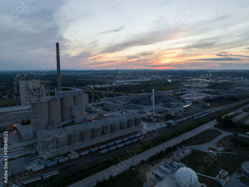 An aerial view looking at a large coal facility at dusk, a beautiful sky in the background.
