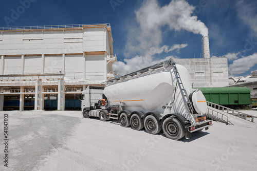 Modern cement trailer near warehouse of production plant