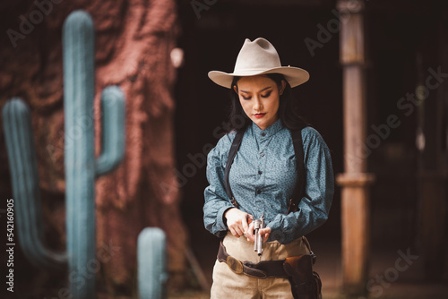 Cowgirl posing with rifle gun on hand to show protected weapon is cowgirl vintage american older style.