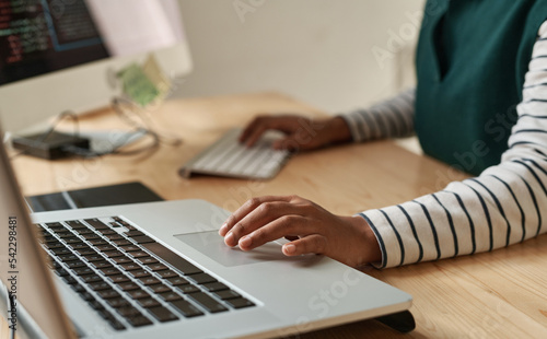 Hand of young black woman over laptop touchpad during network or creation of new website while sitting by workplace in office