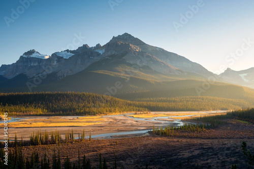 Mountain landscape at dawn. Sunbeams in a valley. Rivers and forest in a mountain valley at dawn. Natural landscape with bright sunshine. High rocky mountains. Banff National Park, Alberta, Canada.