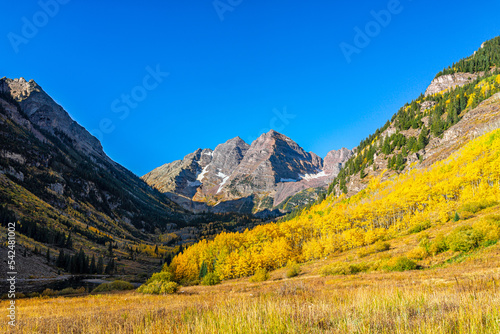 Aspen, Colorado Maroon Bells rocky mountains in October fall autumn season with yellow golden trees foliage and clear blue sky in morning sunrise with nobody