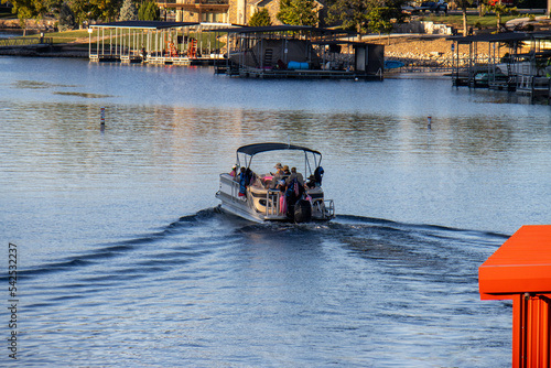 pontoon boat with canopy cruising on lake