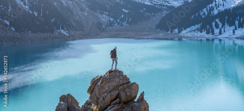 One man standing on a boulder on a vantage point over mountain lake