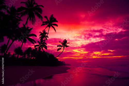 Tropical ocean beach with coconut palm trees silhouettes at dusk after colorful sunset