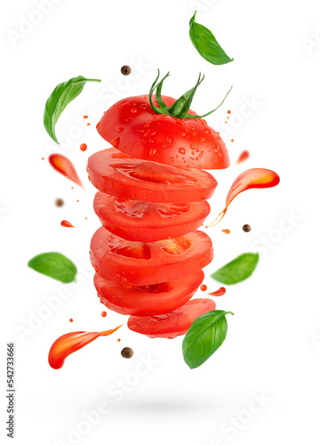 Flying sliced tomato with flowing splashes and basil leaves