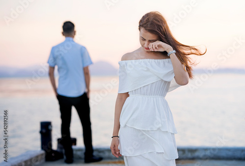 Young couple break up at the sea deck. Girl crying and walk away from man in concept love hurts ,toxic relationship, love story, when love is ended. Broken heart syndrome. How to fix a broken heart.