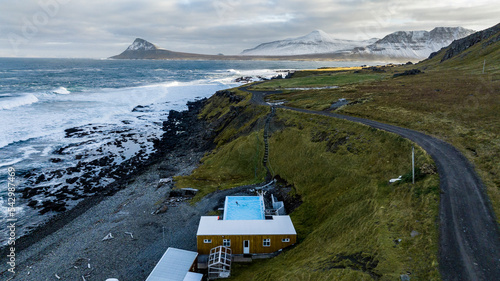 aerial view on gethermal pool in Krossneslaug with fjords on background on the icelandic coast with storm and green grass