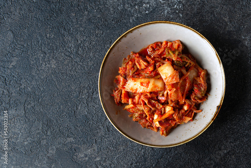 bowl with traditional korean kimchi fermented cabbage on dark table