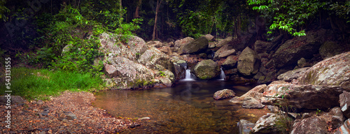 A crystal clear tropical stream with two waterfalls and a water hole surrounded by rocks, gravel, grass, jungle. Australian nature. Far North Queensland. Stoney Creek, Cairns. Landscape photography.