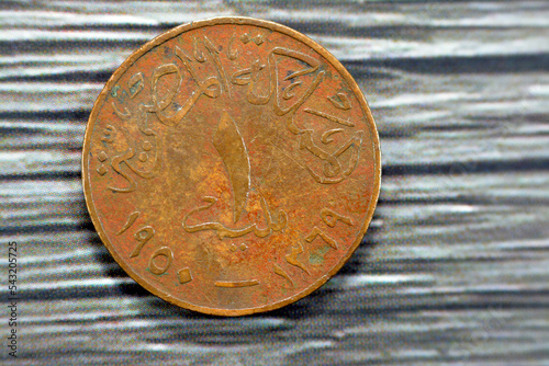 Reverse side of an old 1 One Egyptian red millieme coin year 1950, translation of Arabic text (Egyptian Kingdom,1 Millieme, 1938 - 1357), vintage retro old Egyptian money isolated on wooden background